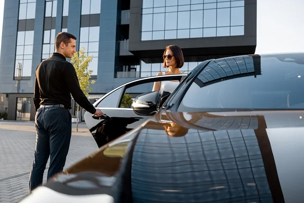 Chauffeur helps an elegant business woman gets in car